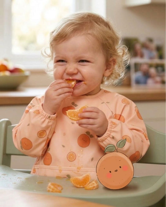 Toddler wearing Tiny Trees orange long sleeve bib